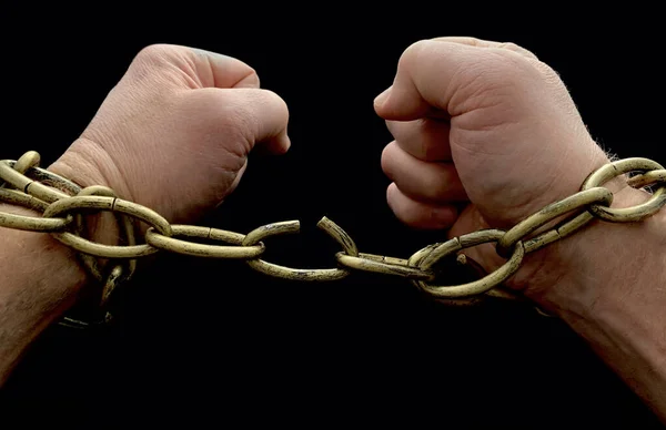 Men's hands break the chain, on a black background. The man is chained, his hands are tied. The concept of freedom, slavery. — Stock Photo, Image