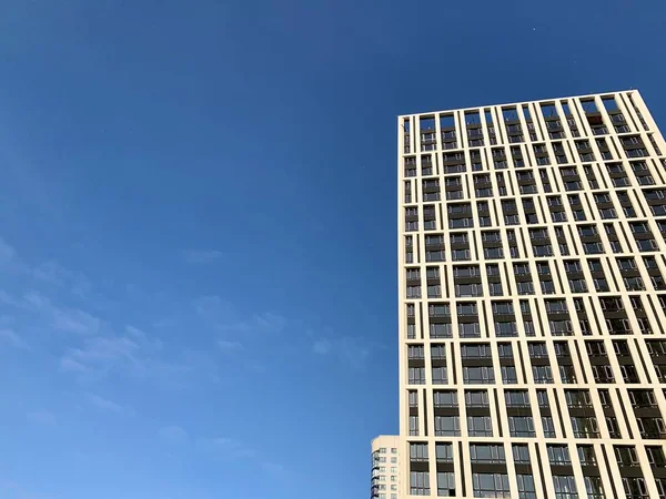 Edifício alto em um fundo de céu azul. Novo edifício alto com janelas espelhadas, vista de baixo. Textura de fundo: edifício de escritórios . — Fotografia de Stock