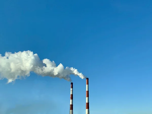 Rauch aus Industrieschornsteinen vor blauem Himmel. Rauch aus Fabrikschornsteinen in einer städtischen Umgebung. Konzept Umweltverschmutzung. — Stockfoto