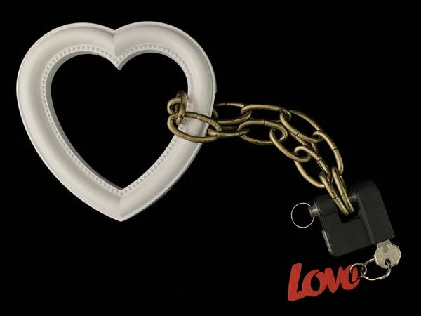 Форма сердца зафиксирована замком на цепи, черный фон. Белое сердце приковано цепью и заперто. Концепция: сердечная связь, сердечная зависимость — стоковое фото