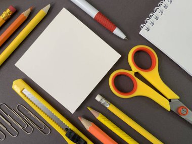 Background texture: school stationery on the desk, yellow and orange. Stationery for the office, free space for writing. Concept: back to school, scissors and paper.