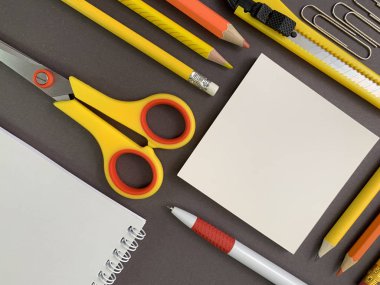 Background texture: school stationery on the desk, yellow and orange. Stationery for the office, free space for writing. Concept: back to school, scissors and paper.