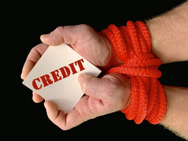 Hands tied with a rope, on a black background. Tied hands are holding a note with the inscription. Concept: loan, debt, help.