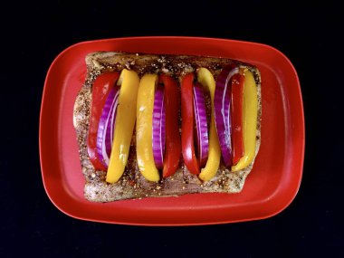 Siyah arka planda, sebzeli büyük bir parça kızarmış et. Biber ve baharatlı biftek pirzolası. Fırında pişirmek için domuz eti ve dana eti..