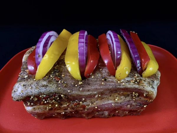 Un trozo grande de carne frita con verduras, sobre un fondo negro. Costillas de filete con pimiento dulce y especias. Cerdo y ternera para hornear en el horno . —  Fotos de Stock