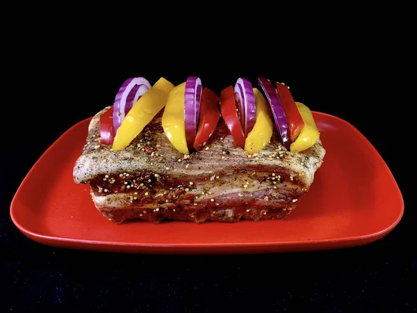 Un trozo grande de carne frita con verduras, sobre un fondo negro. Costillas de filete con pimiento dulce y especias. Cerdo y ternera para hornear en el horno . —  Fotos de Stock