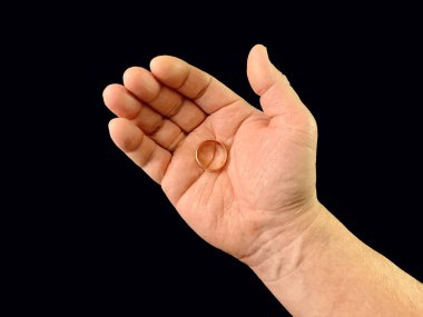 Evlilik yüzüğü bir adamın elinde, siyah bir arka planda. Bir adam avucunun içinde altın bir yüzük tutar. Konsept: Evlen, teklif yap