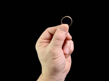 Evlilik yüzüğü bir adamın elinde, siyah bir arka planda. Bir adam avucunun içinde altın bir yüzük tutar. Konsept: Evlen, teklif yap