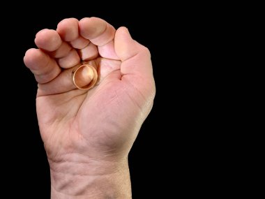 Evlilik yüzüğü bir adamın elinde, siyah bir arka planda. Bir adam avucunun içinde altın bir yüzük tutar. Konsept: Evlen, teklif yap