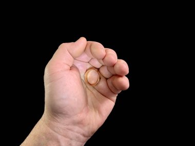 Evlilik yüzüğü bir adamın elinde, siyah bir arka planda. Bir adam avucunun içinde altın bir yüzük tutar. Konsept: Evlen, teklif yap
