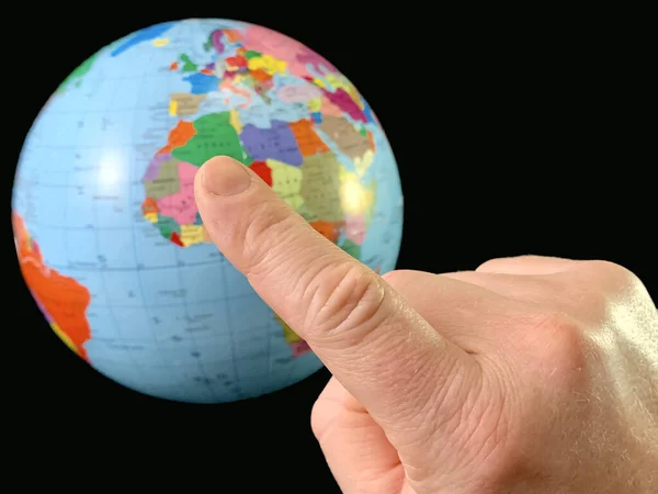 Указательный палец указывает на земной шар на черном фоне. Прикасаясь пальцем к земному шару. Человек держит руку в направлении карты мира. Мбаппе: путешествия, туризм — стоковое фото