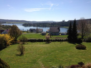Göletin mavi gökyüzüne karşı manzarası. Yaz manzarası, yeşil çimenler ve göl, mesafeyi görüyor. Doğanın ve çimenlerin arasındaki güzel bir nehir manzarası..