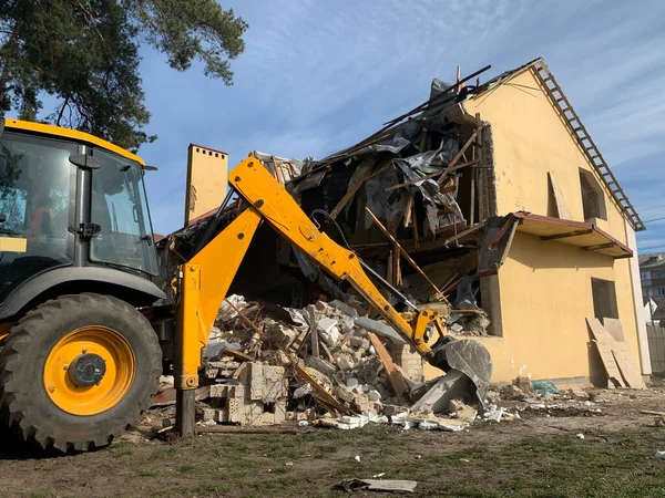 Ruined, brick, residential building. The ruins of a collapsed mansion in the forest. Demolition of an old house with an excavator. The destroyed walls and windows of the building.