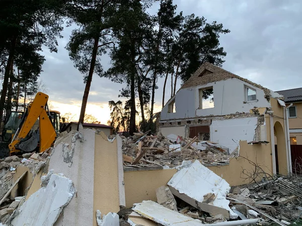 Ruined, brick, residential building. The ruins of a collapsed mansion in the forest. Demolition of an old house with an excavator. The destroyed walls and windows of the building.