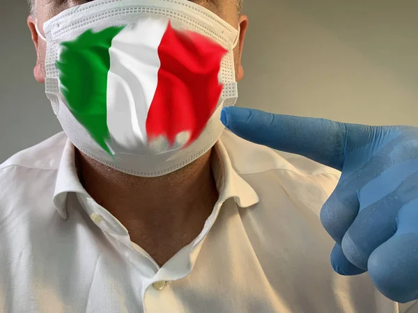 Man in medical mask with flag of italy. The male face is covered with a protective medical mask in a glove. Concept: coronavirus epidemic, spread of pneumonia, pandemic, Covid-19