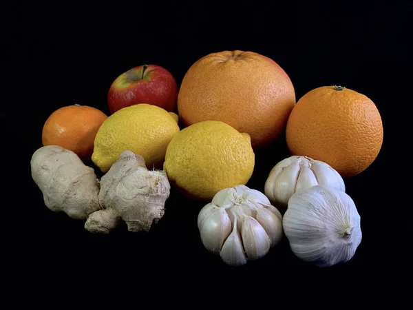 Garlic, ginger, apple and citrus fruits on a black background. Natural vitamins on the table, oranges, grapefruit and mandorin. Concept: Prevention of viral infections and corovirus at home.
