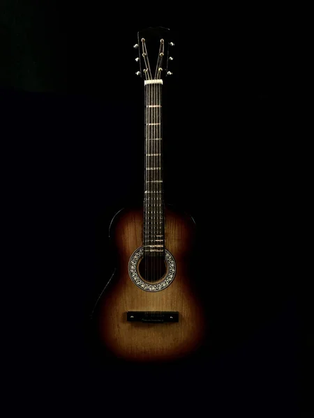 Six-stringed acoustic guitar on a black background. Musical string instrument. Guitar fretboard with strings.