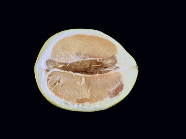 Kesik içinde olgun bir Pamela, siyah bir arka planda. Yarım büyük greyfurt. Kavram: narenciye diyeti, doğal vitaminler, egzotik meyveler.