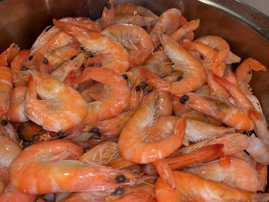 Metal kasede kaynamış karides. Büyük pembe bir karides tabakta yatıyor. Deniz lezzeti kavramı..