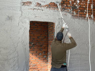 Sanatçı alçıyı tuğla duvara yapıştırıyor. İnşaatçı duvar kaplamalarıyla meşgul. Ressam, sıva makinesi ile çalışıyor..