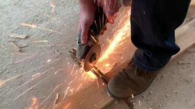 Elmas öğütme tekerleğinden kıvılcımlar çıkıyor. Usta bir aletle metal bir çubuğu keser. İşçi inşaatçısı güçlendirilmiş çeliği kesti.