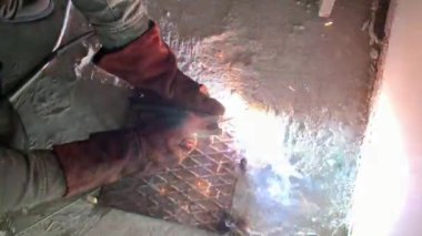 Kaynakçının işi sırasında kaynak makinesinden çıkan kıvılcımlar. Usta, metal bir çubuğu aletle lehimliyor. İşçi inşaatçısı güçlendirilmiş çeliği kesti.