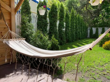 Evin terasında rahatlamak için boş hamak. Bahçede yeşil bir bahçede bir hamak asılı. Konsept: açık hava eğlencesi, hafta sonu parkta.