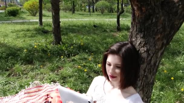 Jeune fille charmante jouant sur la tablette dans le parc de la ville, 4K, UHD, UltraHD Séquence Vidéo