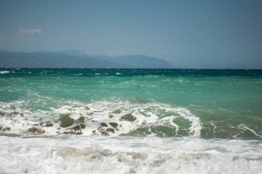 Küçük deniz dalgaları çarpıyor ve köpük yapıyor.