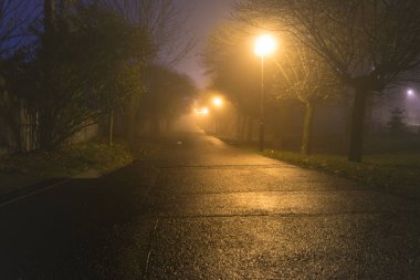 Karanlık sokakta iluminated puslu soğuk geceleri sokak lambaları tarafından. 