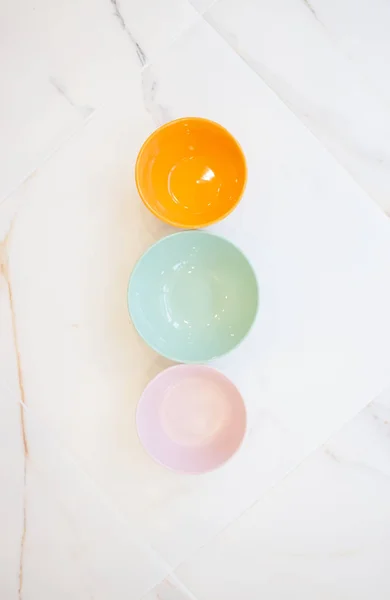 Placas de mármol blanco. tazones sin comida de diferentes colores, vista superior, diseño plano. rosa, azul, naranja — Foto de Stock