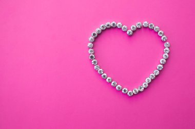 Pembe arka planda sahte taşlardan yapılmış bir kalp ve metin alanı. Sevgililer Günü planı