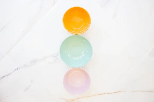 Assiettes sur marbre blanc. bols sans nourriture de différentes couleurs, vue de dessus, disposition plate. rose, bleu, orange — Photo