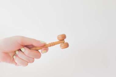 Kız elinde ahşap bir yüz silindiri tutuyor. Kozmetik masaj, gençlik, yaş, lüks ve güzel bir ürün. Boşluğu kopyala