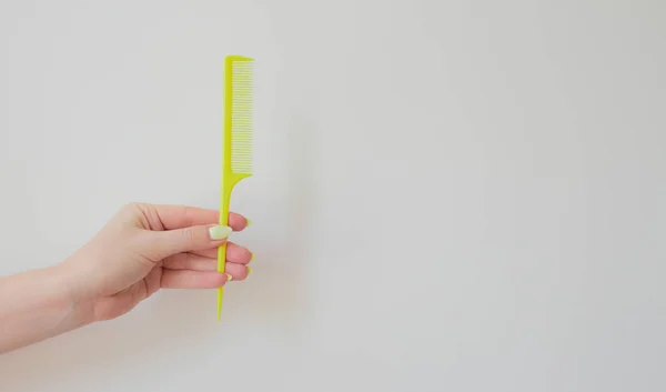 Pente de cabelo amarelo em um fundo branco na mão de uma jovem mulher. disposição — Fotografia de Stock