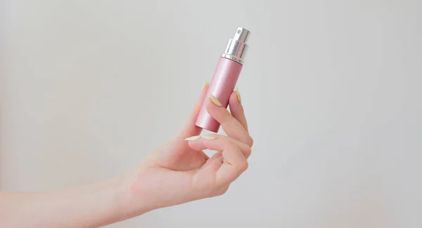 Mujer joven sosteniendo una botella de perfume en la mano. botella de metal con spray en un blanco. cosmetología patrón de belleza . — Foto de Stock