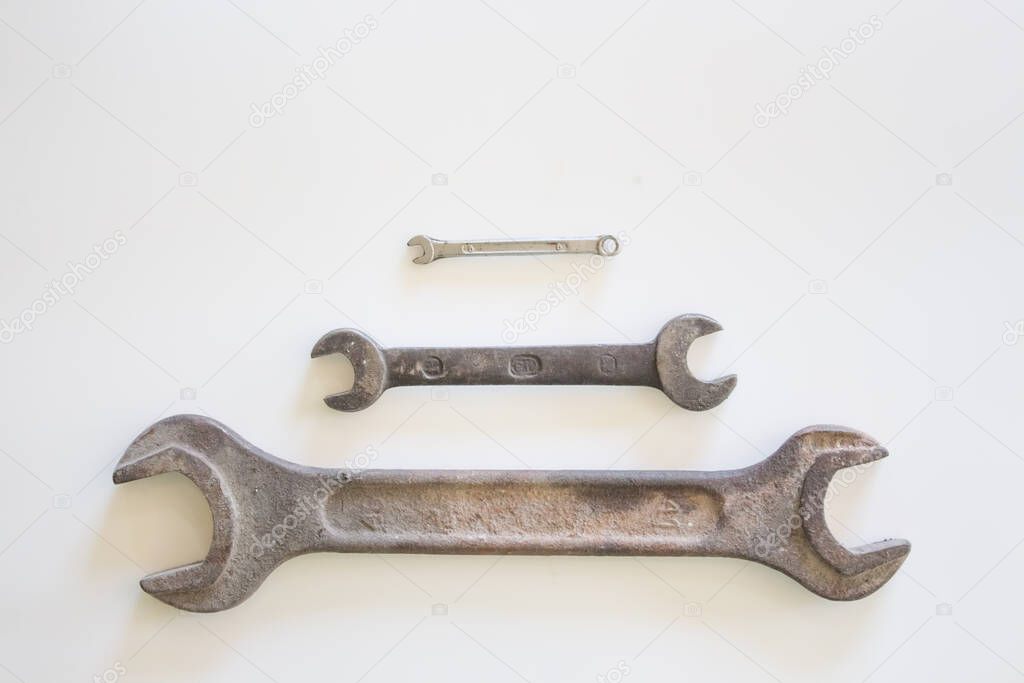 Old rusty wrench on a white and metal background. several wrenches of different sizes. Card with copy space for text.