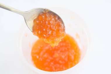  Beyaz arka planda metal kaşıkta kırmızı havyar. Havyarlı banka. Üst Manzara. Model yap. Metin için boşluk.