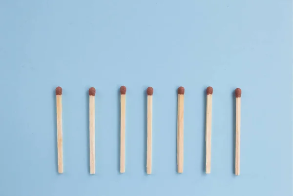 matches in a row on a blue background, down arrow from matches. Top view. Mock up. Flat lay composition.