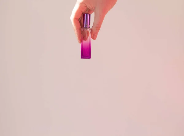 Uma jovem mulher segura uma garrafa de maquete de perfume em um fundo branco na sombra. Conceito de aroma. Minimalismo — Fotografia de Stock