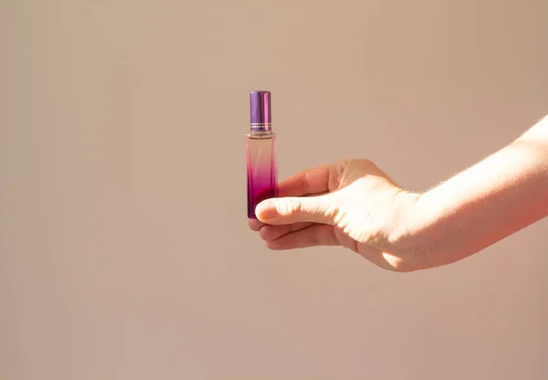 Egy fiatal nő egy üveg parfüm mockup-ot tart egy fehér háttérben az árnyékban. Aroma fogalom. Minimalizmus — Stock Fotó