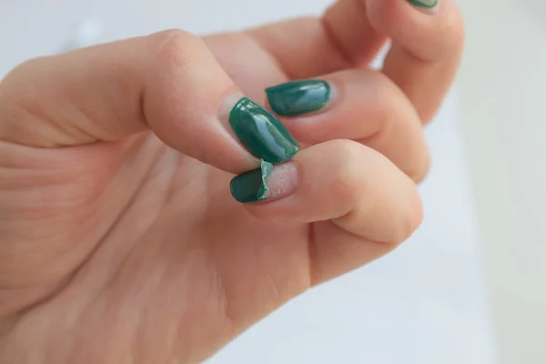 Unha feminina danificada com manicure verde. Descascado gel polonês com unhas. Conceito de manicure em casa — Fotografia de Stock