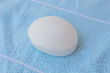  Pamuklu kumaşın mavi arka planında beyaz sabun. Spa konsepti, ev cilt bakımı, sivilce tedavisi. Üst görünüm, düz görünüm.