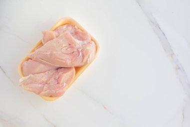 Beyaz mermer bir masada çiğ tavuk filetosu. Üst Manzara. Düz konum.