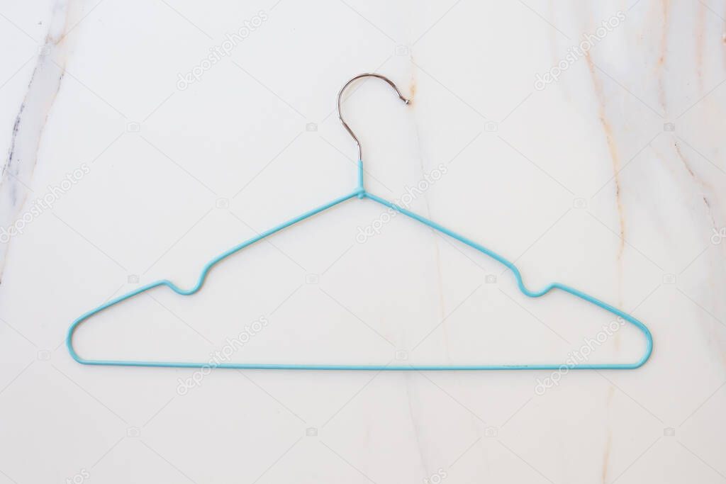  Flat lay set of blue hangers on white marble. Many colored hangers lying chaotically, minimal concept.
