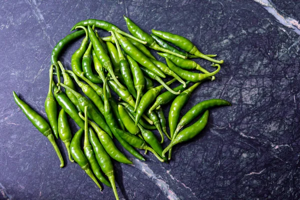 Fresh harvested green chili on green marble texture background.top view.