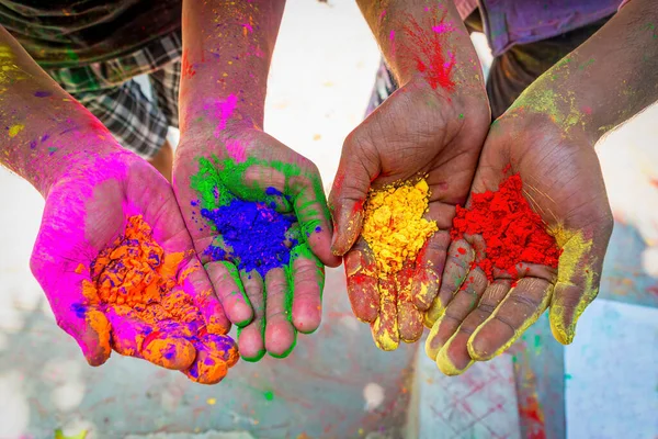 Hands fully covered with red, green, yellow, pink colored gulal or holi powder.Happy holi.