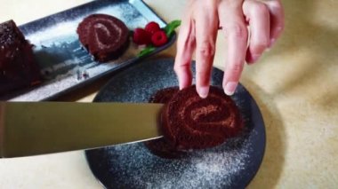 İsviçre dürümü ahududu ile süslenmiş. Ev hanımı uzanır ve çikolatalı İsviçre böreği süsler..