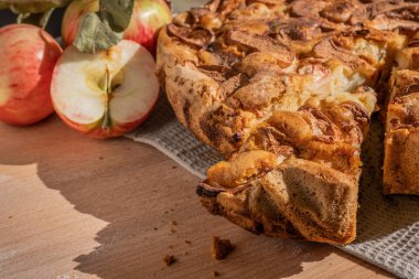 Mutfaktaki ahşap masada elmalı turta ve taze elmalar.