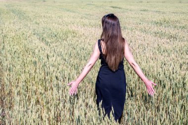 Siyah elbiseli bir kadın buğday tarlasında yürüyor. Wheat fi
